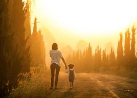 mère et enfant se tenant la main au coucher du soleil avec espace de copie, vue de dos photo