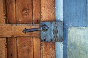 fragment d'une vieille porte en bois avec une poignée en acier forgé. photo