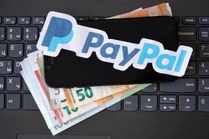 ternopil, ukraine - 6 septembre 2022 le logotype papier payoneer se trouve sur un ordinateur portable noir avec des billets en euros. payoneer est une société américaine de services financiers qui propose des transferts d'argent en ligne photo