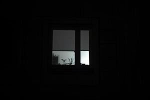 la fenêtre est dans le noir. lumière de la fenêtre la nuit. détails du bâtiment dans l'obscurité totale. photo