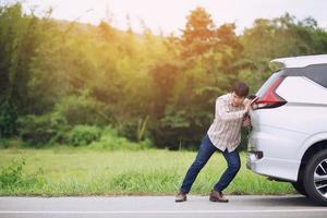 un jeune homme stressé ayant des problèmes avec son accident de salle des machines de voiture cassée par le stress à un moteur en panne attend de l'aide. photo