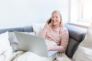 heureuse jeune femme gaie parlant au téléphone à la maison, adolescente souriante répondant à un appel par téléphone portable assis sur un canapé, belle dame ayant une conversation amusante et agréable parlant par mobile photo