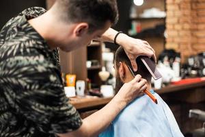 rasoir dans les mains d'un coiffeur professionnel. coiffeur rasant le cou de l'homme avec un rasoir droit photo