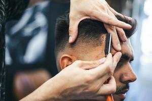 rasoir dans les mains d'un coiffeur professionnel. coiffeur rasant les cheveux de l'homme avec un rasoir droit photo