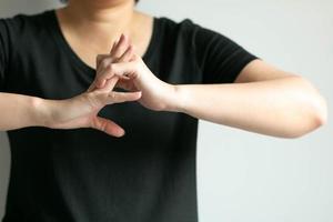 gros plan d'une femme en t-shirt noir craque ses jointures après avoir travaillé dur en utilisant la main et les doigts. photo