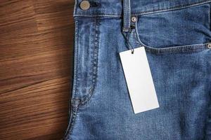 Jeans bleu avec étiquette de prix blanc vierge sur fond de bois photo