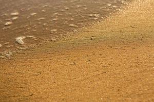 fond avec du sable doré sur la côte de l'île de crète. surface abstraite avec du sable et de l'eau de mer claire pour le texte. photo