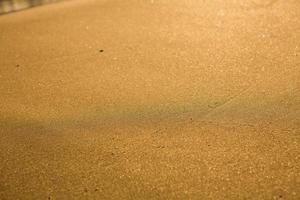 fond avec du sable doré sur la côte de l'île de crète. surface abstraite avec du sable et de l'eau de mer claire pour le texte. photo