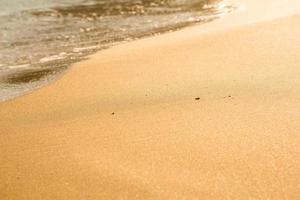fond avec du sable doré sur la côte de l'île de crète. surface abstraite avec du sable et de l'eau de mer claire pour le texte. photo