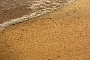 fond avec du sable doré sur la côte de l'île de crète. surface abstraite avec du sable et de l'eau de mer claire pour le texte. photo