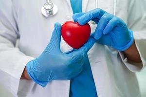 femme médecin asiatique tenant un coeur rouge pour la santé à l'hôpital. photo