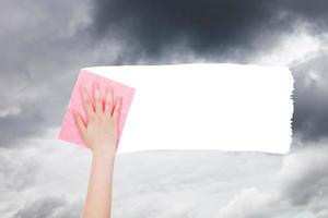 la main supprime les nuages gris du ciel par un chiffon rose photo