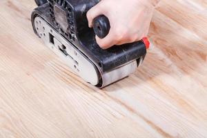 finition de la surface en bois à l'aide d'une ponceuse à bande manuelle photo