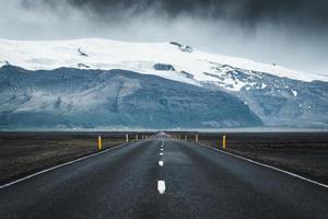 route goudronnée droite avec tempête sur la montagne par une journée sombre en islande photo