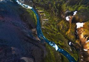 montagne volcanique surréaliste pittoresque avec rivière à travers un champ de lave situé à distance dans les hautes terres d'islande