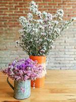gros plan de belles fleurs dans un vase sur une table en bois et un fond de mur de briques floues. photo