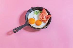 petit-déjeuner sain œuf au plat dans une poêle à frire sur une table rose. photo