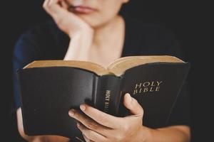 main de jeune femme tenant la sainte bible avec étude à la maison. livre de lecture chrétienne femelle adulte à l'église. fille apprenant la spiritualité religieuse avec prier Dieu. concept de foi en éducation des étudiants. photo