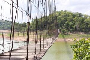 pont suspendu sur la rivière avec montagnes et ciel en arrière-plan photo