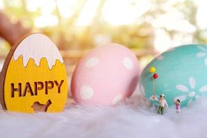 famille de personnes miniatures tenant un ballon avec des oeufs de pâques pastel et colorés, concept de vacances et de joyeuses pâques photo