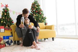 beau jeune couple tient des verres de champagne, souriant et se regardant tout en célébrant le nouvel an à la maison photo