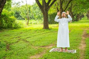 homme musulman asiatique debout et priant tout en levant les bras sur la dune photo