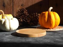 podium en bois sur une table en bois rustique avec de petites citrouilles pour la maquette ou l'affichage du produit dans le concept d'automne. la lumière naturelle du soleil. photo