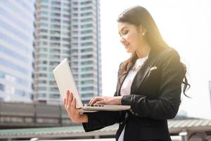 une photo d'une femme d'affaires travaillant sur son ordinateur portable en plein air