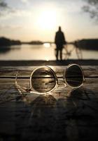 un coucher de soleil calme sur un lac avec une paire de lunettes de soleil au premier plan photo