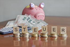 L'orthographe des lettres steuer - allemand pour les taxes - sur de petits tas de pièces en euros - déclaration de revenus photo