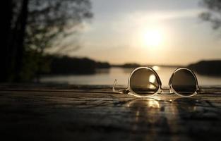 un coucher de soleil calme sur un lac avec une paire de lunettes de soleil au premier plan photo