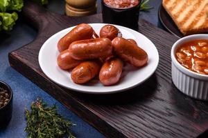 petit-déjeuner anglais traditionnel avec œufs, pain grillé, saucisses, haricots, épices et herbes sur une plaque en céramique grise photo