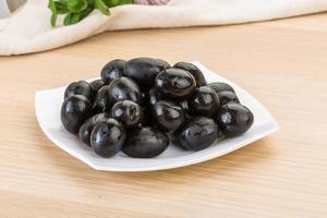 olives noires sur la plaque et fond en bois photo