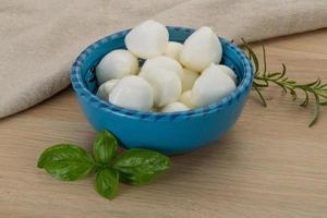 Fromage mozzarella dans un bol sur fond de bois photo