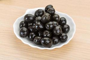 olives noires sur la plaque et fond en bois photo