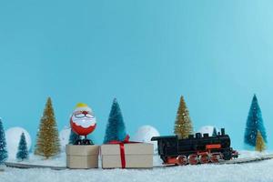 le père noël transporte des cadeaux dans un train à travers la forêt. joyeux Noël. bonne année photo