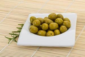 olives vertes dans un bol sur fond de bois photo