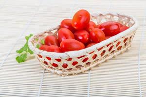 tomate cerise dans un panier sur fond de bois photo