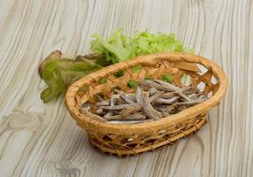 anchois sèche dans un panier sur fond de bois photo