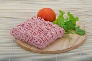 Viande de porc hachée crue sur planche de bois et fond de bois photo