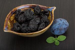 prunes séchées dans un bol sur fond de bois photo