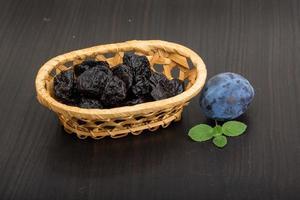 prunes séchées dans un panier sur fond de bois photo