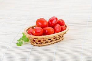 tomate cerise dans un panier sur fond de bois photo