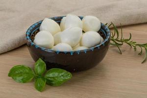 Fromage mozzarella dans un bol sur fond de bois photo