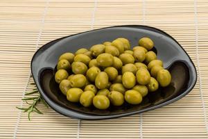 olives vertes sur la plaque et fond en bois photo