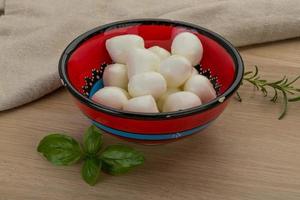 Fromage mozzarella dans un bol sur fond de bois photo