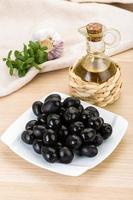 olives noires sur la plaque et fond en bois