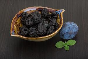 prunes séchées dans un bol sur fond de bois photo