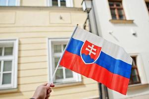 drapeau de la slovaquie en main contre la rue de bratislava. photo
