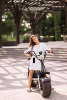 belle jeune femme et un scooter électrique, transport écologique photo